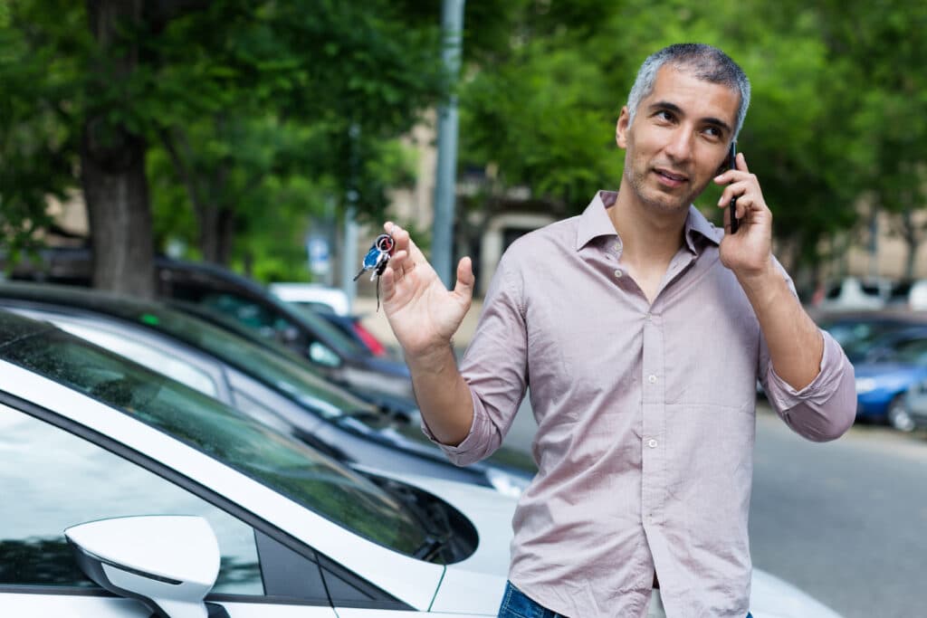 homem fala ao cleualr ao lado de carro, recebe dicas de cuidados com o carro
