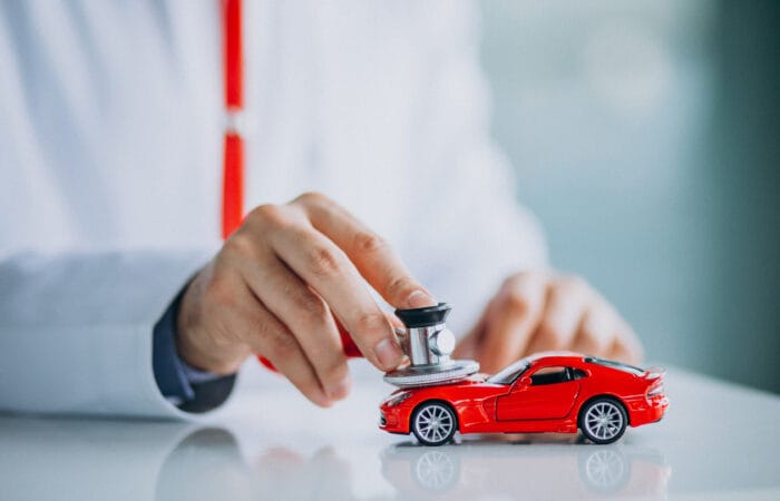 Carro recebendo manutenção com profissional especializado, simbolizando um plano de saúde automotivo.