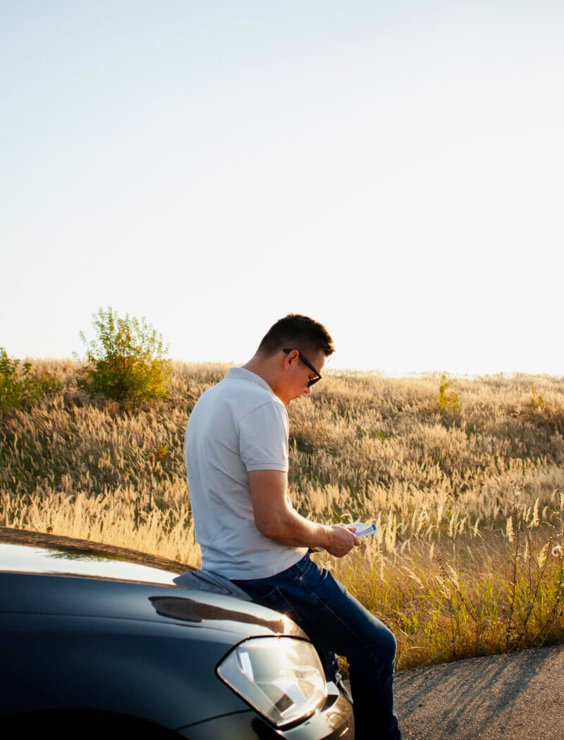 young man resting car hood