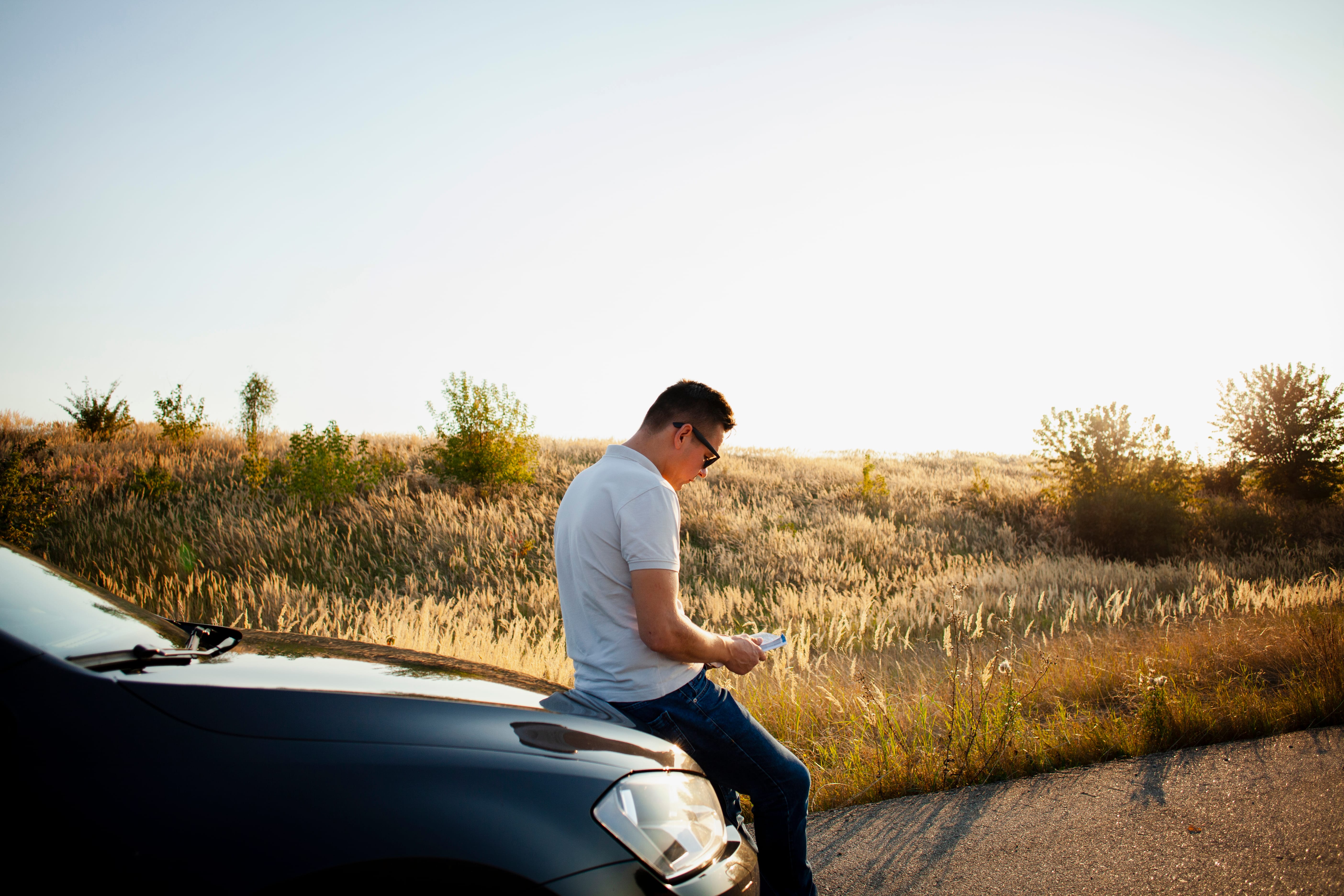 young man resting car hood